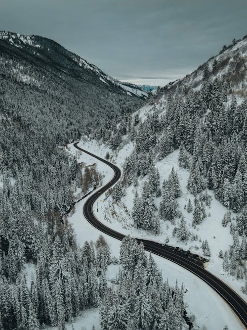 Black Asphalt Road in the Middle of Snow Covered Mountain