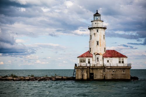 Free Scenic view of the Chicago Harbor Lighthouse with a partially cloudy sky and calm Lake Michigan waters. Stock Photo