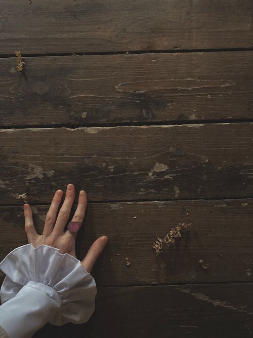 Free A hand with a flower ring rests on a vintage wooden surface with scattered petals. Stock Photo