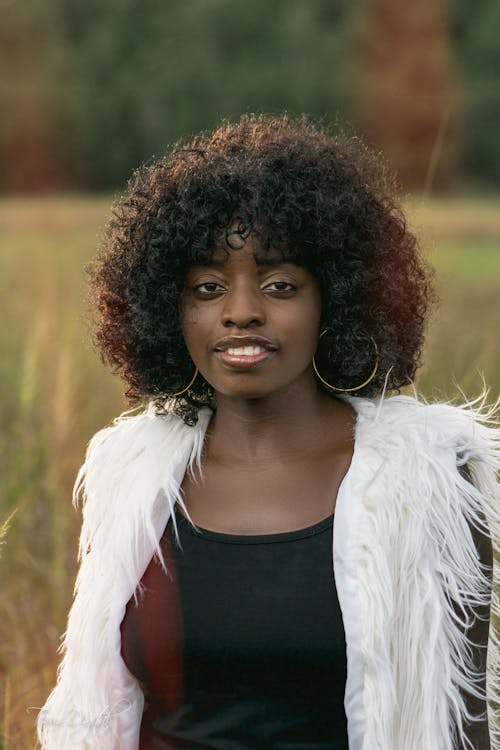 Selective Focus of a Curly-Haired Woman Wearing Her White Fur Vest