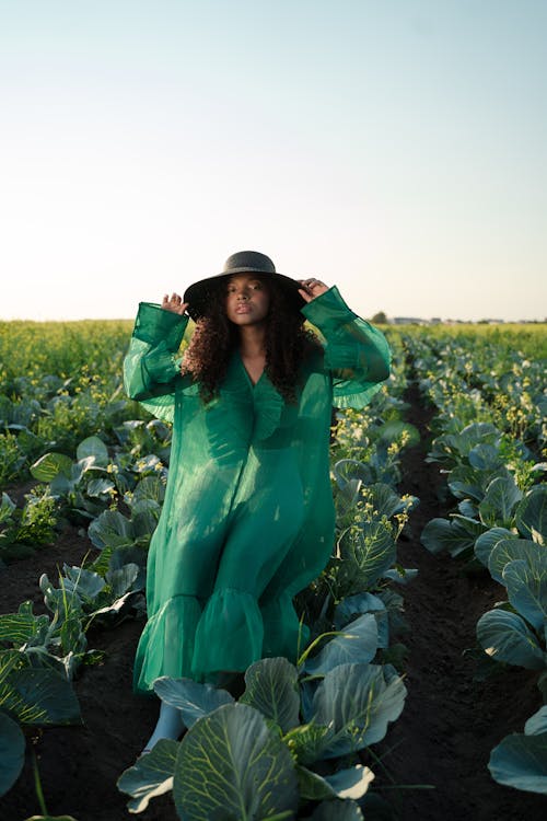 Portrait of Curly Haired Woman with Hat Against Field of Cabbage
