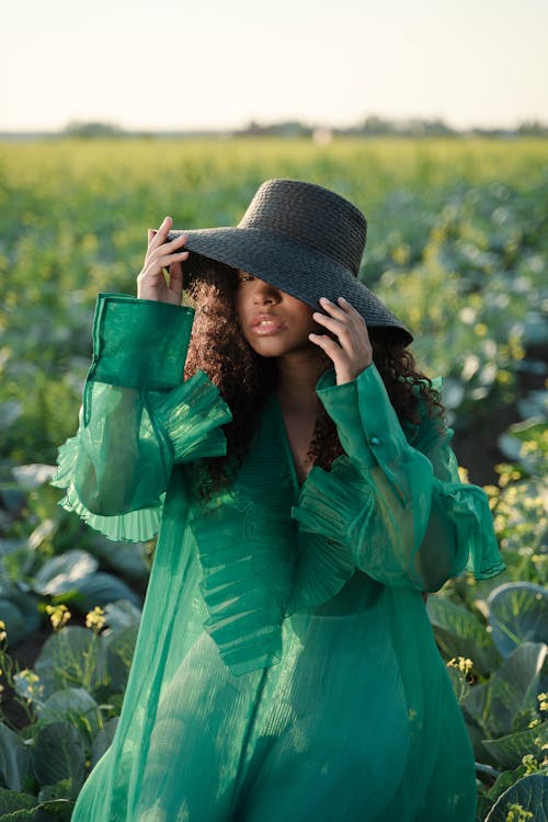 Portrait of Woman in Green Dress and Wide Brim Hat Sitting in Cabbage Field