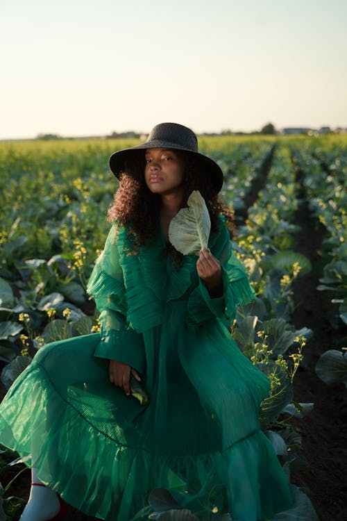 Curly Haired Woman in Green Dress Holding Cabbage Leaf