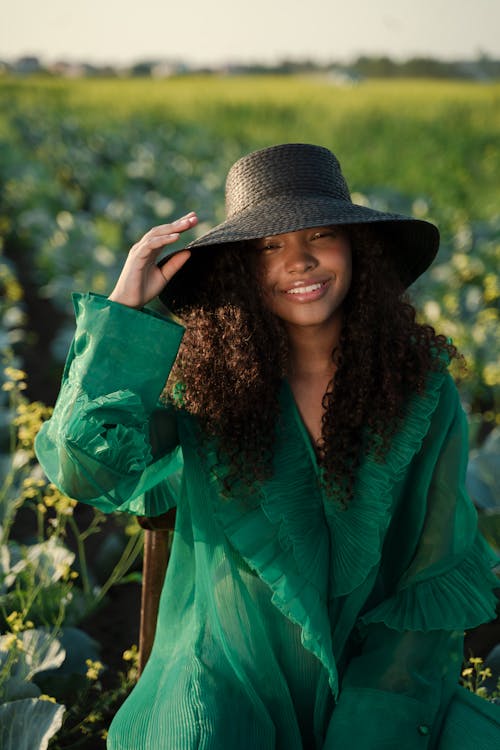 Woman in Green Dress and Wide Brim Hat Sitting in Cabbage Field