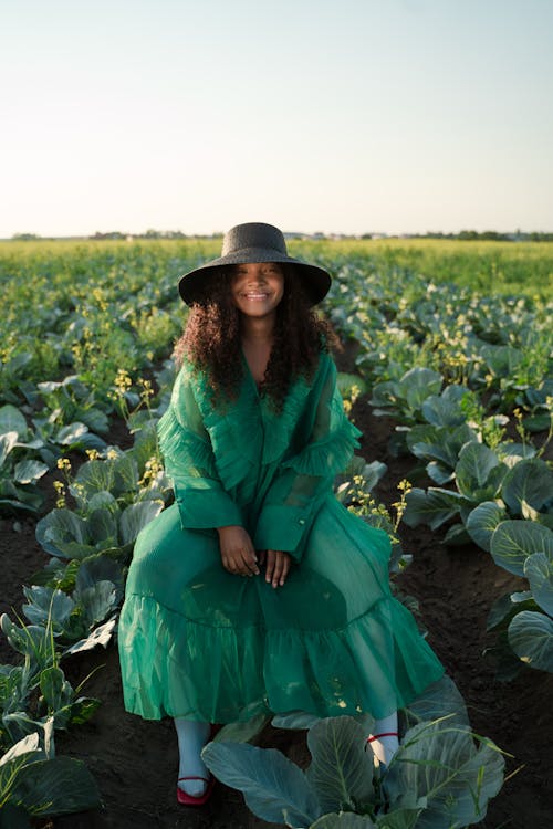 Curly Haired Woman in Dress Against Field of Cabbage