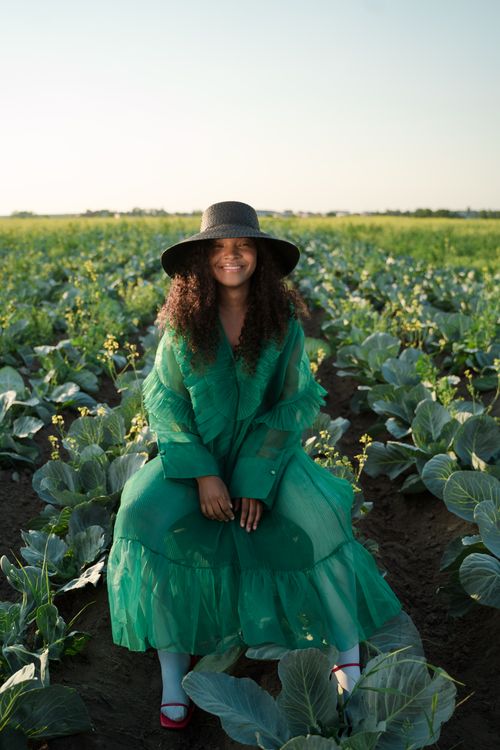 Free A smiling woman in a green dress and hat sitting in a cabbage field. Stock Photo