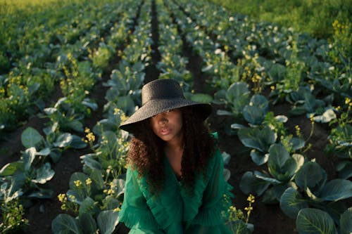 Curly Haired Woman in Green Dress Against Cabbage Field