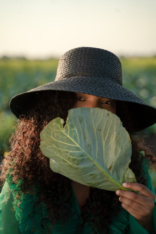 Portrait of Woman in Hat Holding Cabbage Leaf