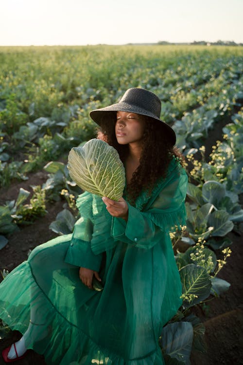Kneeling Woman in Hat Holding Cabbage Leaf