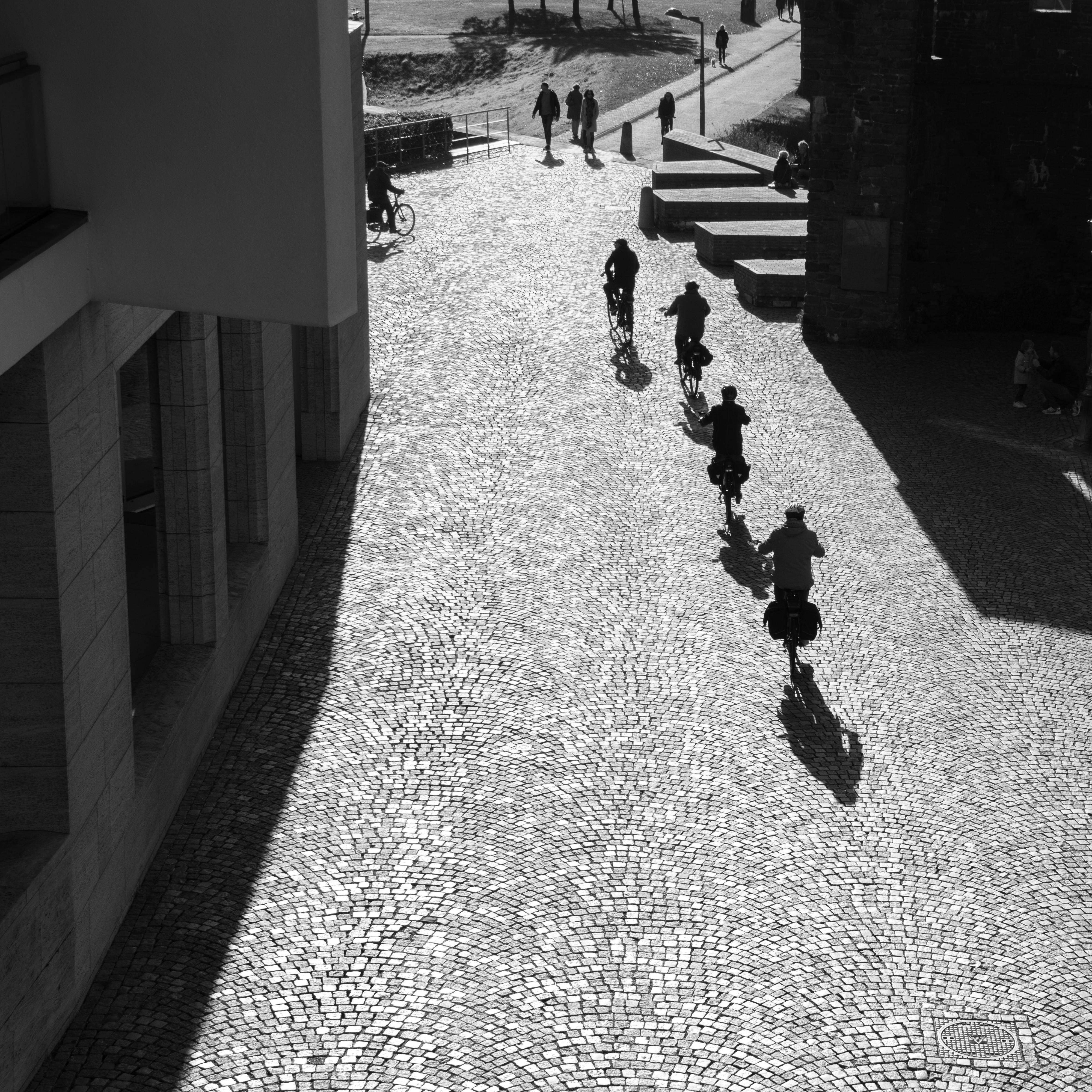 Black and white scene of cyclists on a cobblestone street in Maastricht.