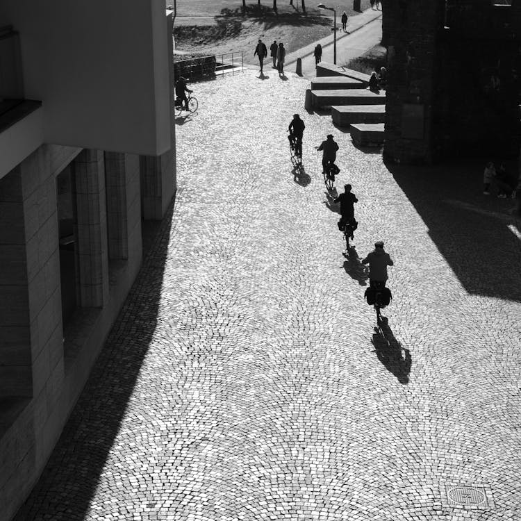 Grayscale Photo Of People Biking On Street