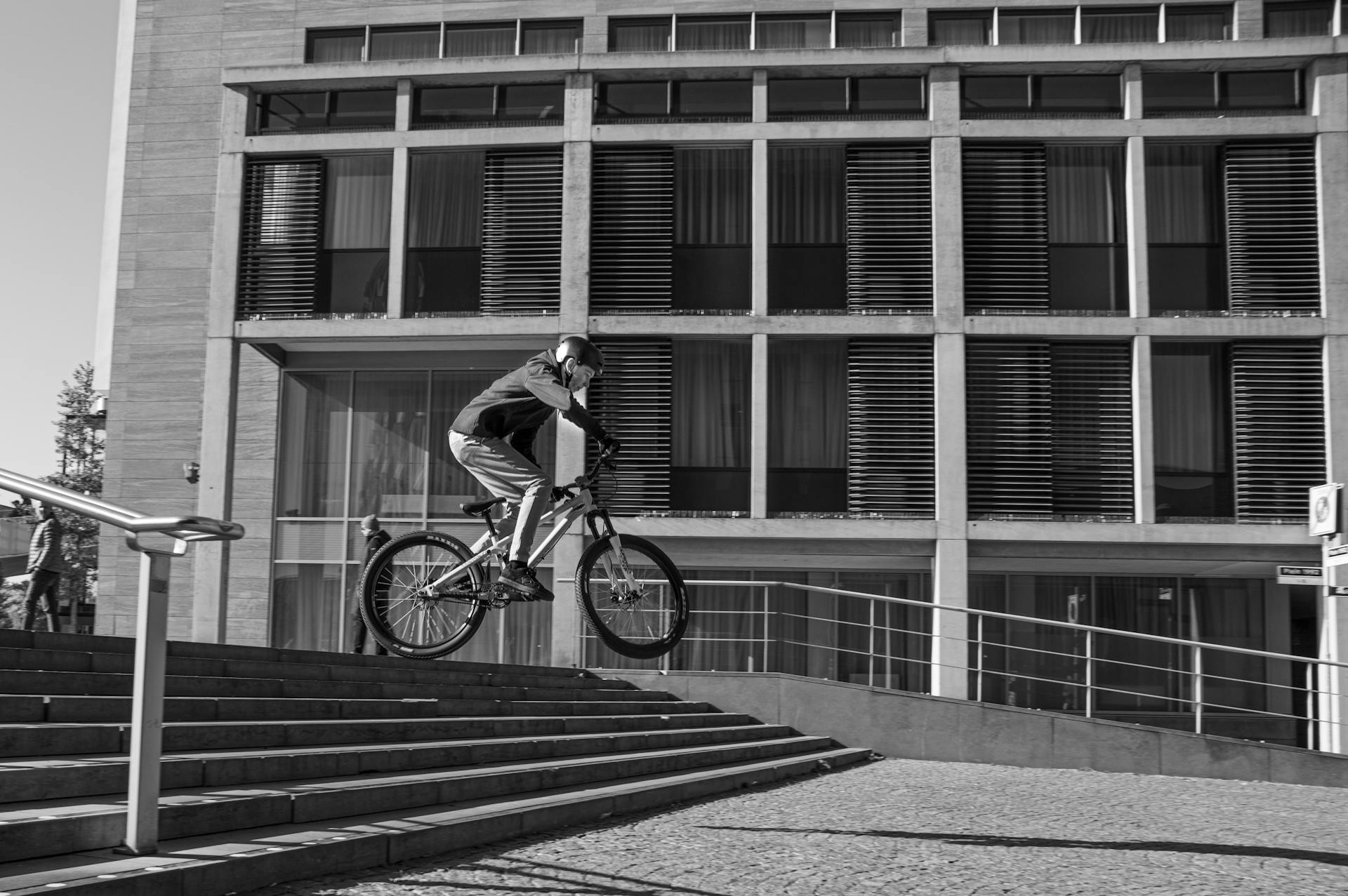 BMX rider performs a freestyle stunt on steps in urban Maastricht setting.