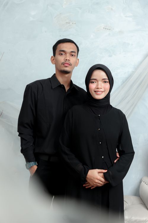 Free A relaxed portrait of a smiling couple in black attire with a soft background. Stock Photo