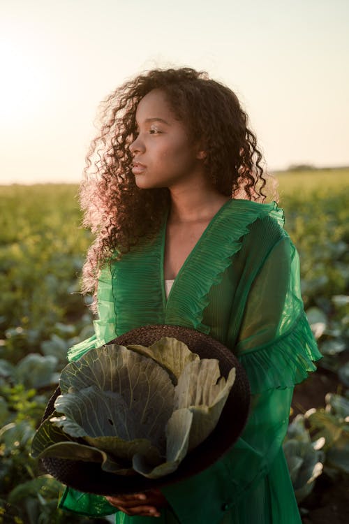 Woman in Green Dress in Cabbage Field at Sunset