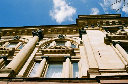 Free A low-angle view of an ornate historical building facade against a clear blue sky. Stock Photo