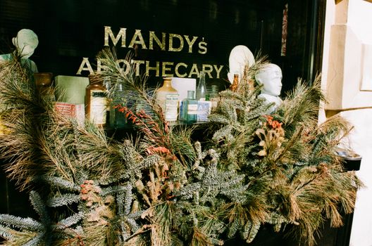 A festive storefront with vintage apothecary items and holiday greenery.