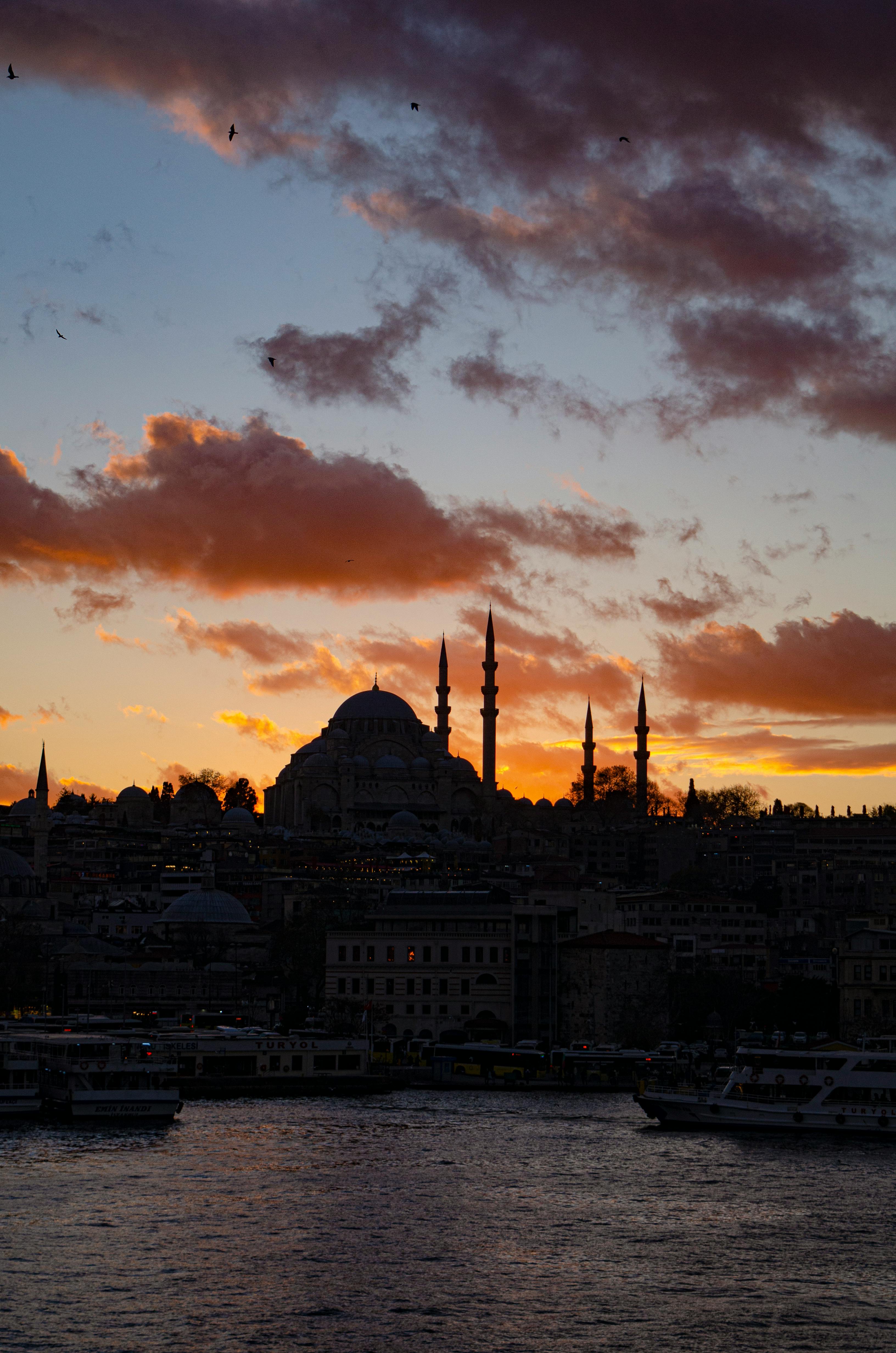 silhouette of city buildings under cloudy sky during sunset