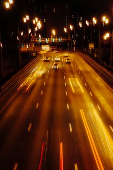 Vivid long exposure shot of cars speeding on a highway at night, capturing vibrant light streaks.