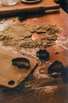 Close-up of rustic cookie dough with metal cutters on a wooden surface, ready for baking.