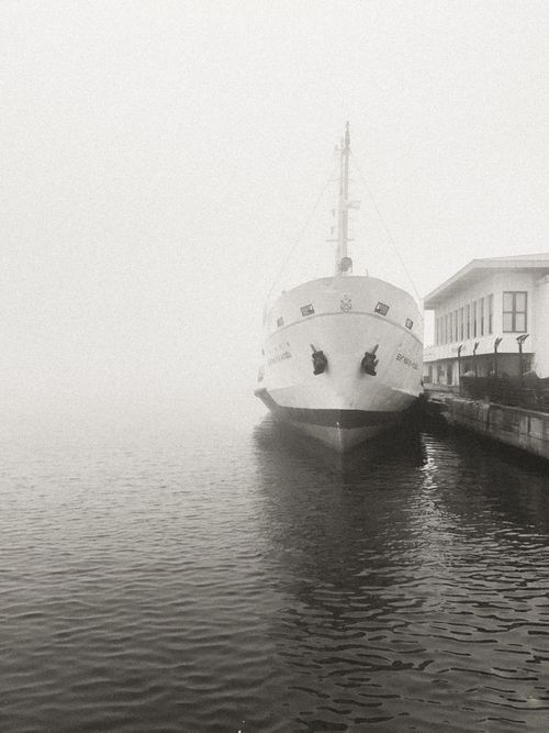 Free A serene view of a ship docked at a foggy harbor, capturing tranquility and stillness. Stock Photo