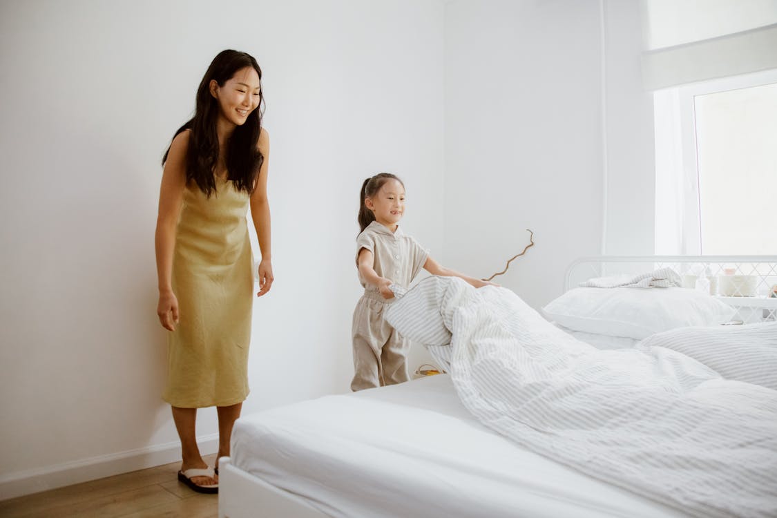 Daughter Making a Bed and Mother Looking at Her