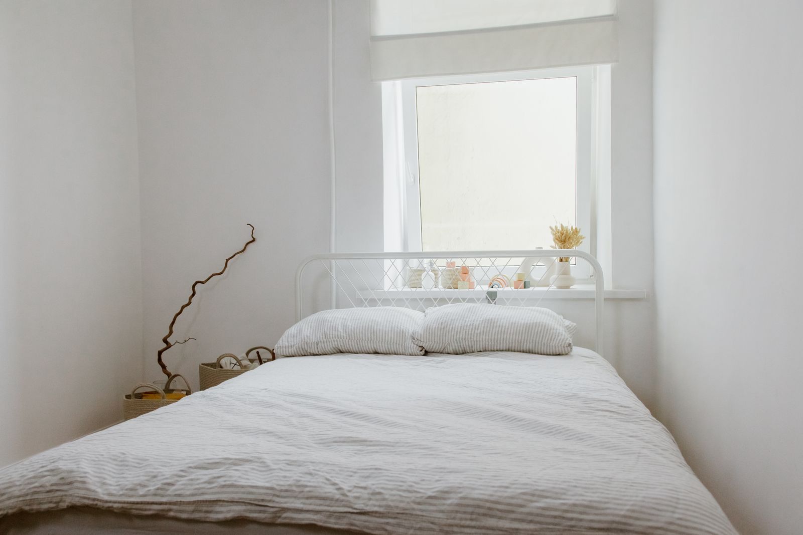 A white bedroom with the bed placed under the window
