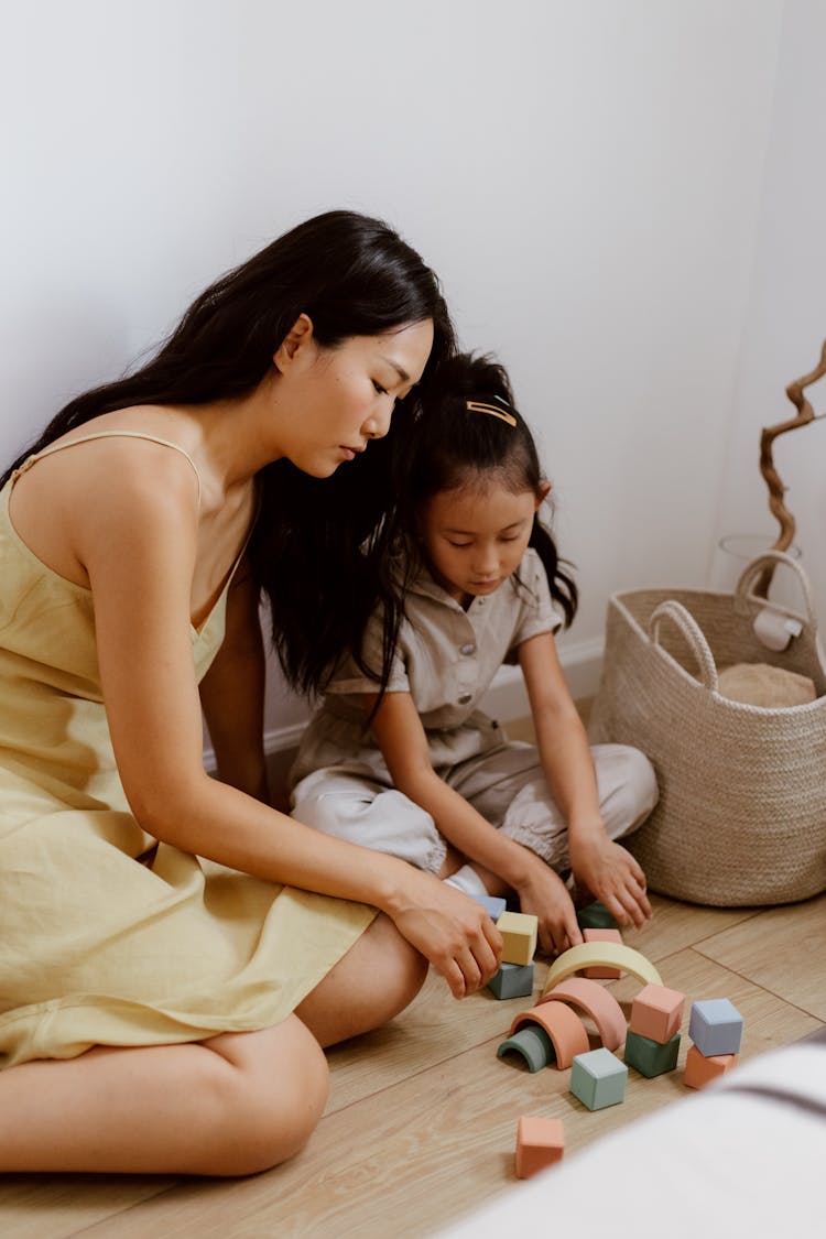 Mother And Daughter Playing With Building Blocks On The Floor