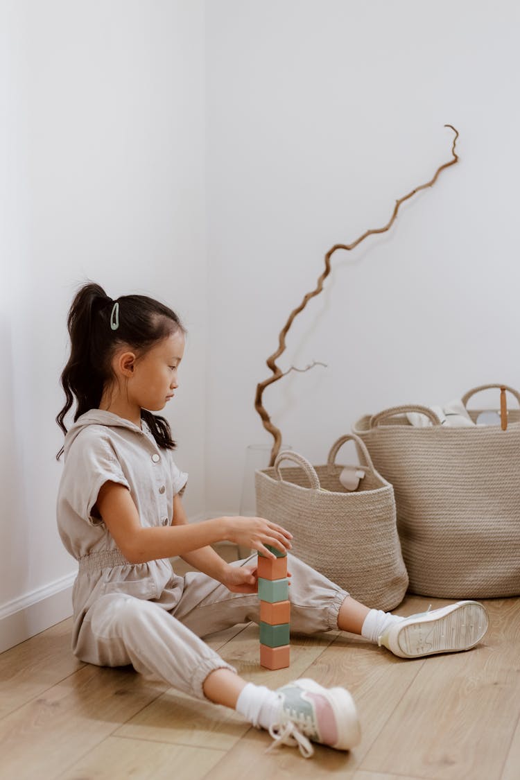 Girl Sitting On The Floor And Building A Tower Of Blocks 