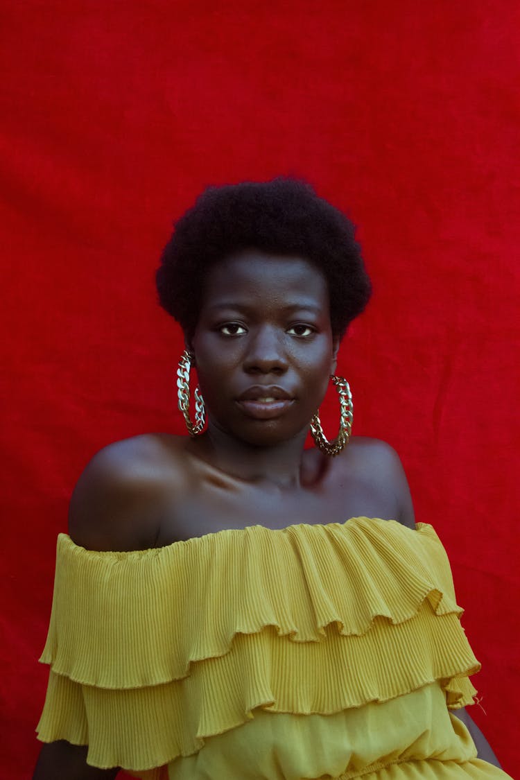 A Woman In Yellow Off Shoulder Top With Hoop Earrings