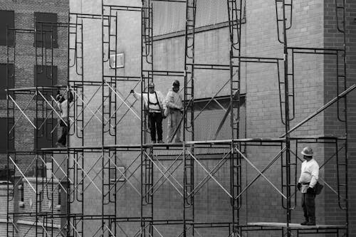 Construction Workers Walking on a Scaffolding Outside of a Building in City 