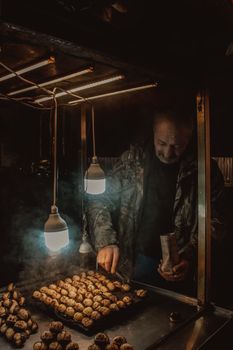 A street vendor sells roasted chestnuts from a cart under warm light in Istanbul.