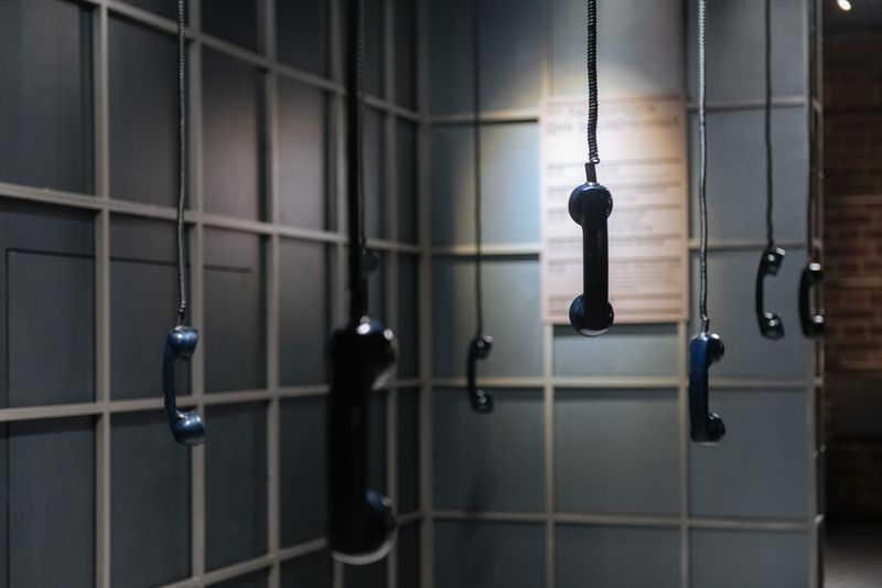 Artistic display of hanging vintage telephone receivers in a gallery. Unique and thought-provoking.