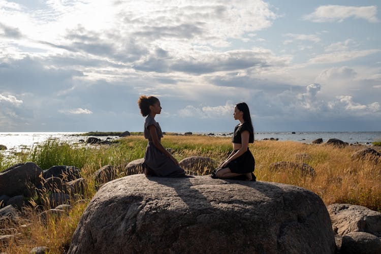 Women Sitting On Brown Rock