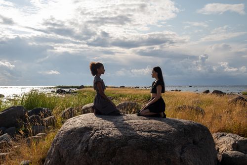 Free Two women meditating on rocks by the sea, promoting wellness and serenity. Stock Photo