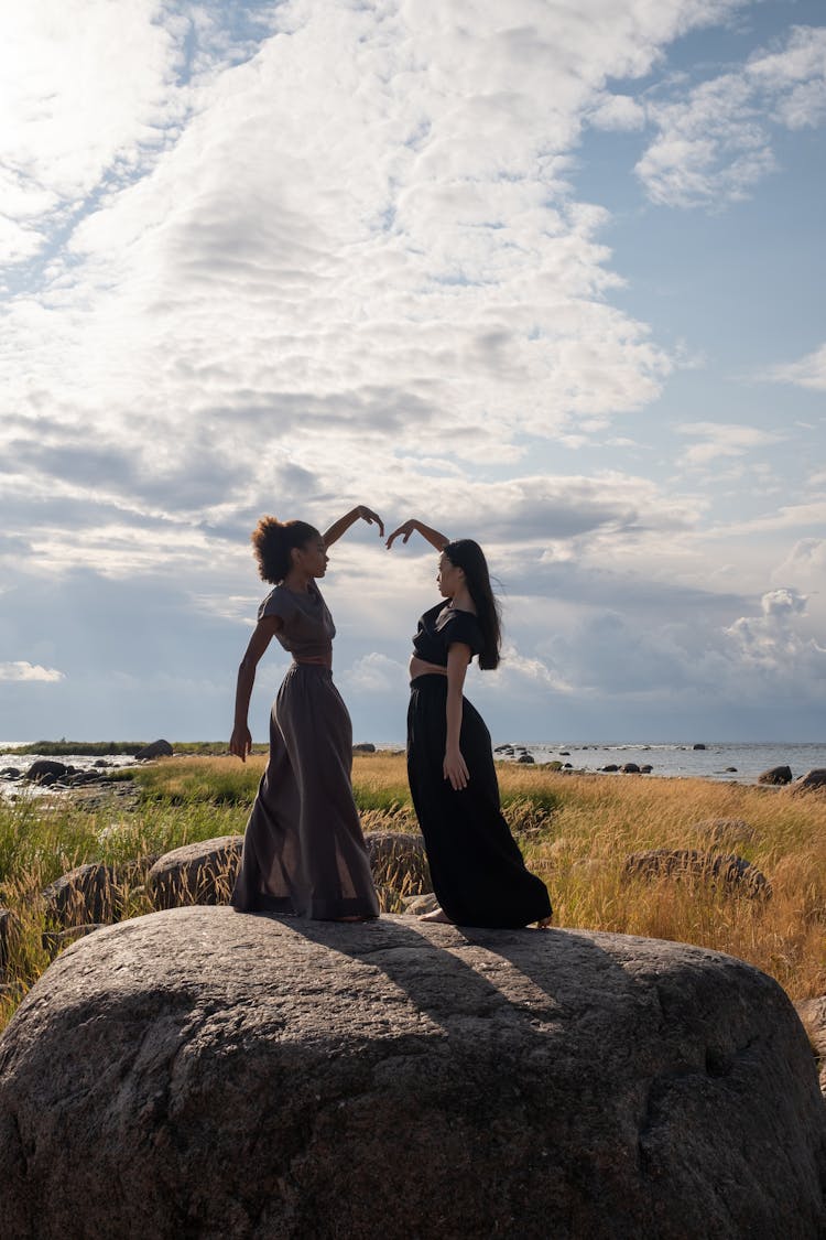 Women Dancing Together On Top Of A Rock