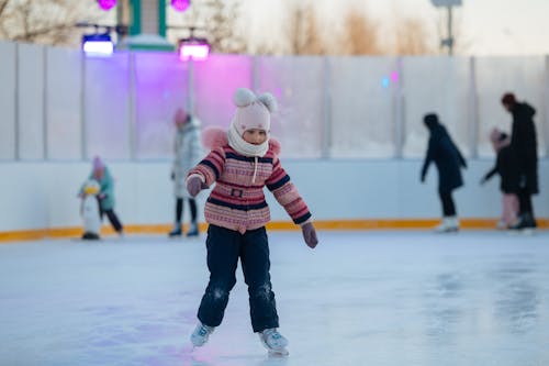 A Young Girl in Knitted Sweater Skating on the Rink