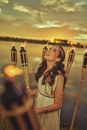 A Woman in White Dress Looking Up while Holding a Torch