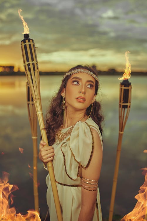 Free A Woman in Greek Dress Holding a Bamboo Holder with Oil Lamp  Stock Photo