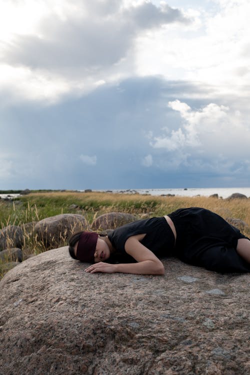 A Blindfolded Woman Lying on a Rock