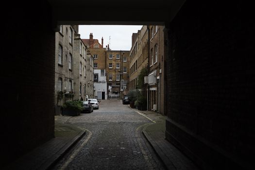 A picturesque cobblestone alley surrounded by historic buildings in a quiet European town.