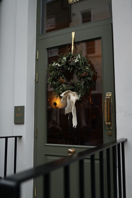 A festive holiday wreath adorns a green exterior door, adding charm and warmth to the entrance.