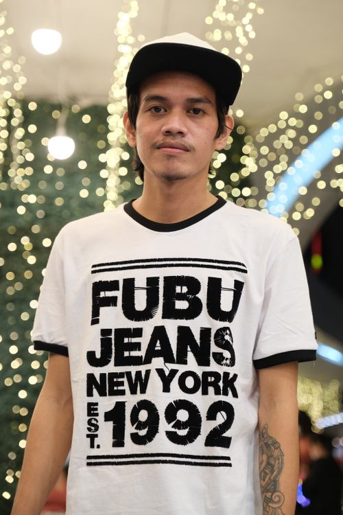 Free Man wearing a FUBU jeans t-shirt standing against a festive light background. Stock Photo