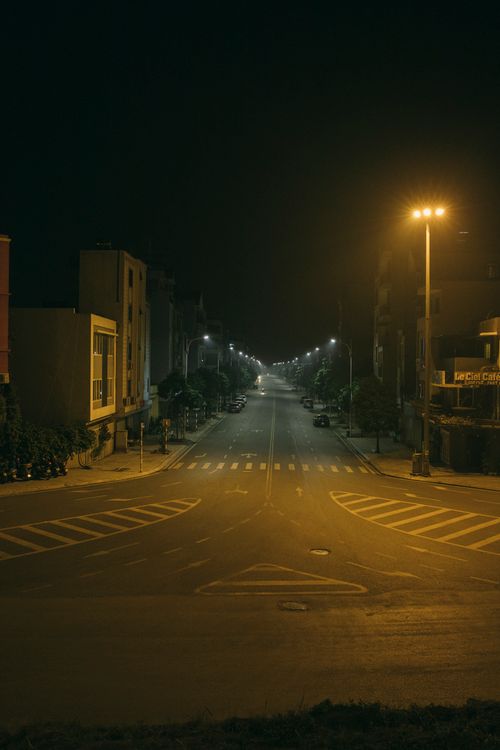 Free A tranquil urban street scene at night with atmospheric street lighting and empty roadways. Stock Photo