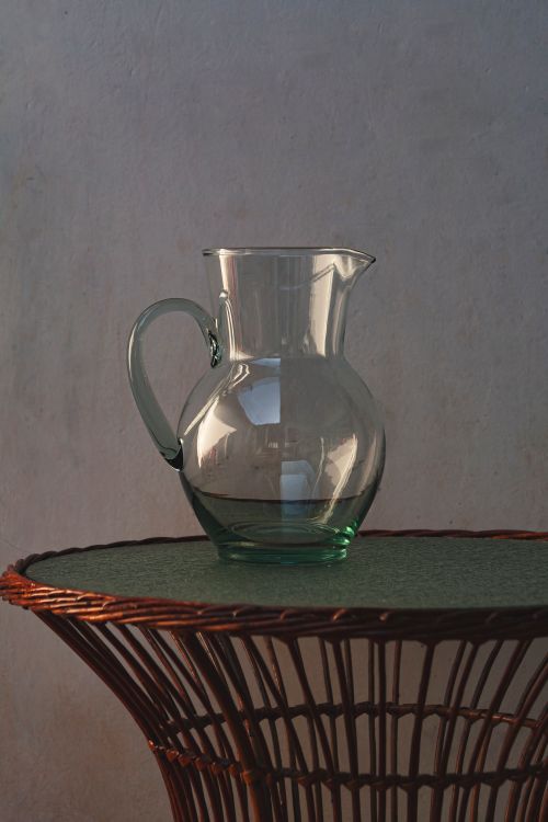 Free Glass pitcher on a wicker table with a neutral background. Stock Photo