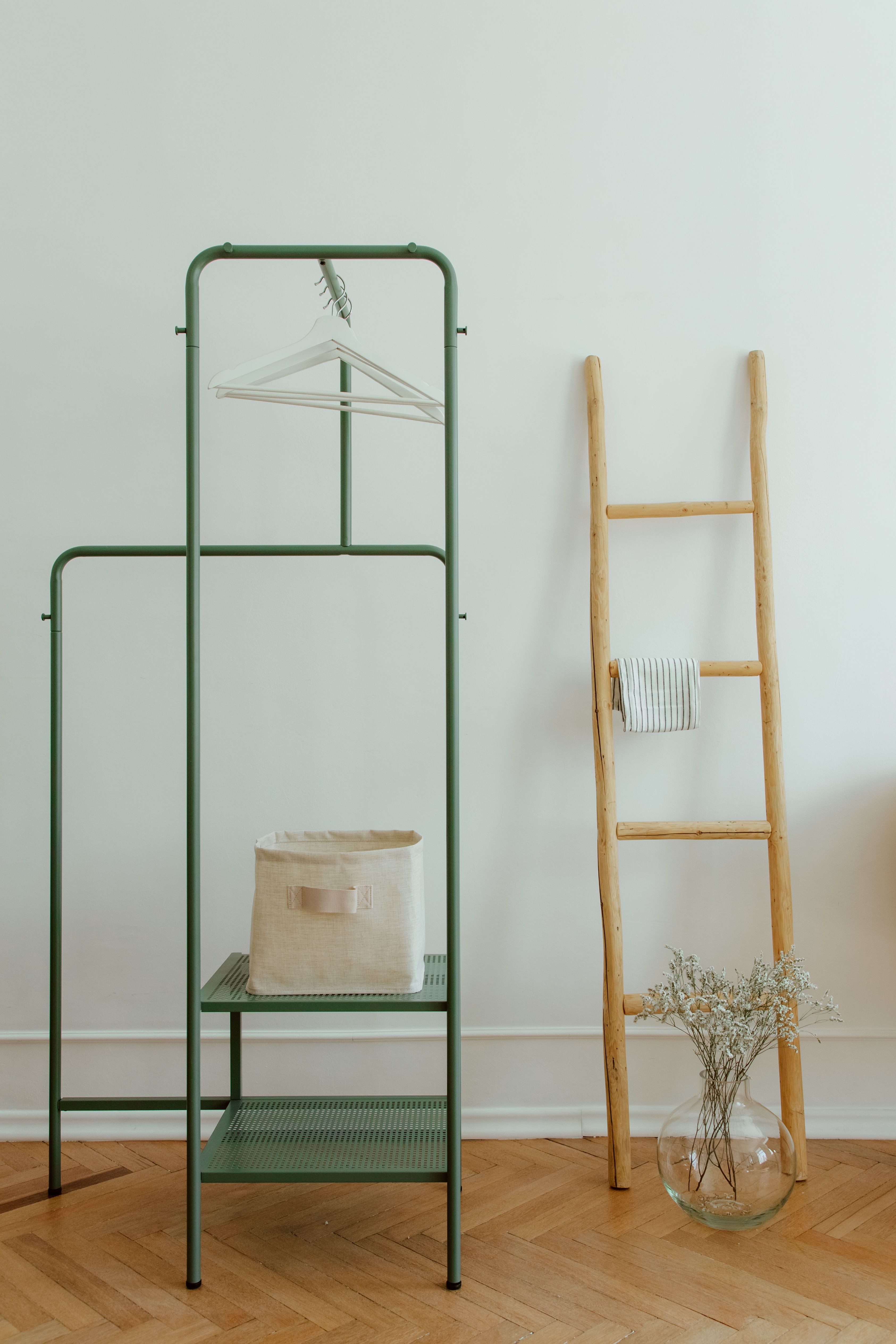 A clean and simple home interior featuring a wooden ladder and a minimal clothing rack.