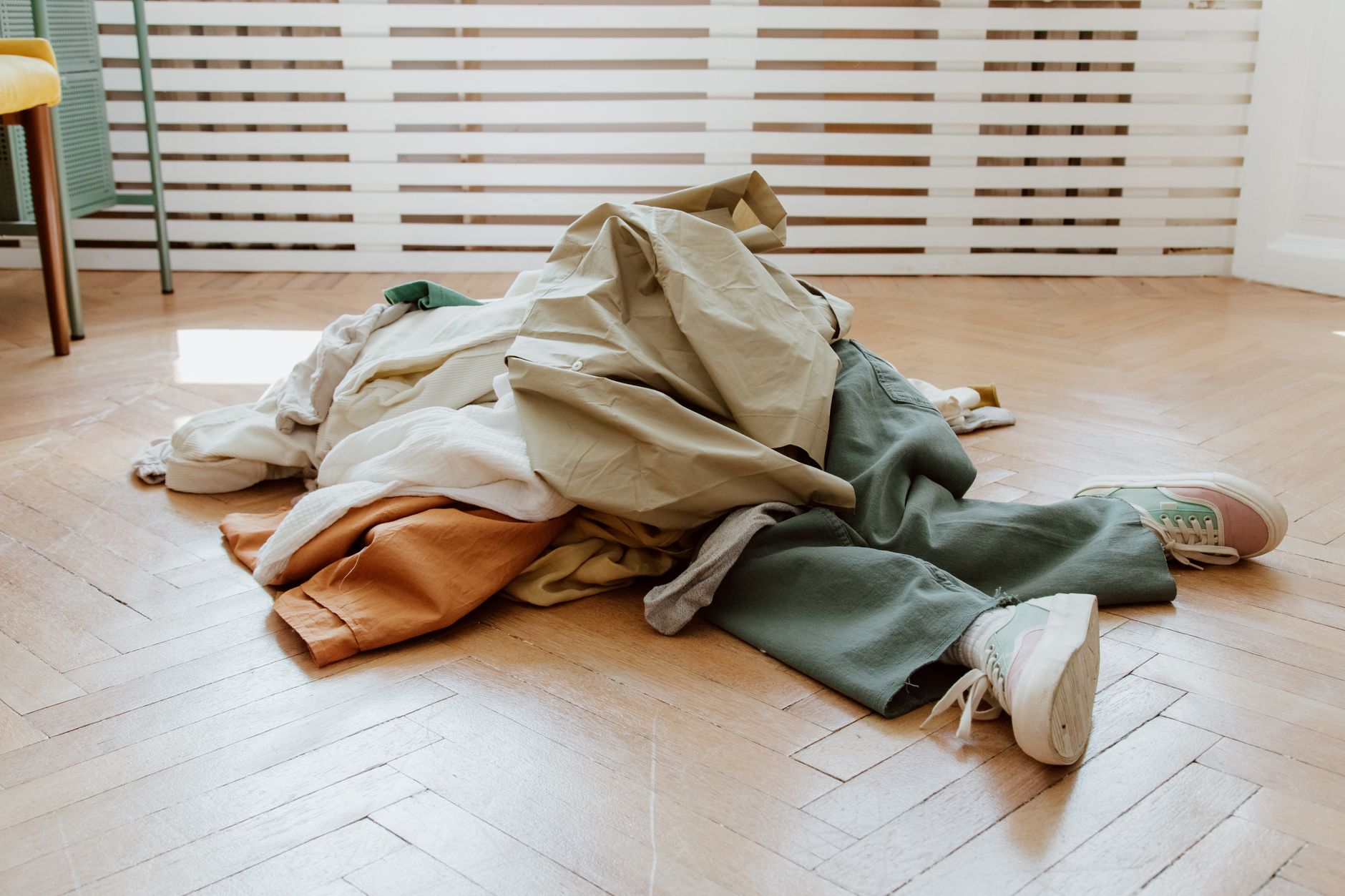 A wardrobe audit in progress with garments sorted into keep, repair, and release piles on a bed