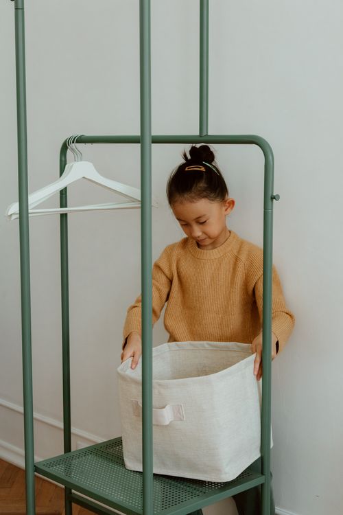Free A young girl organizing items in a living room using a storage basket. Stock Photo