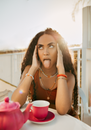 Young Woman Sitting at Table and Showing Her Tongue