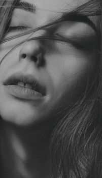 Close-up black and white portrait of a woman with eyes closed, capturing emotion.