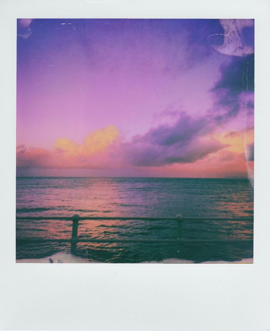 Vintage Polaroid capturing a stunning sunset over the ocean with vibrant skies.